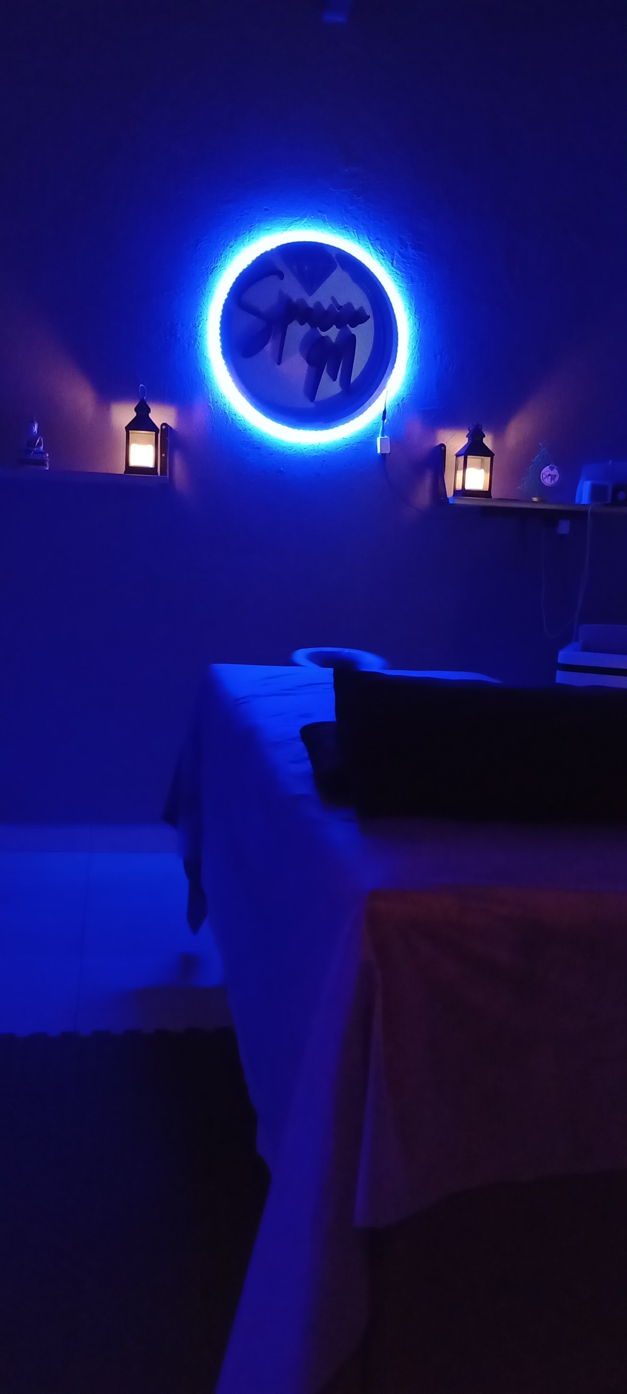 Camilla de masajes en suite nocturna con letrero neón en Spacio M